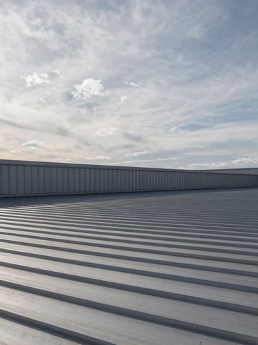 Heroic wide architectural angle of a modern commercial metal roof under high-contrast overcast skies.