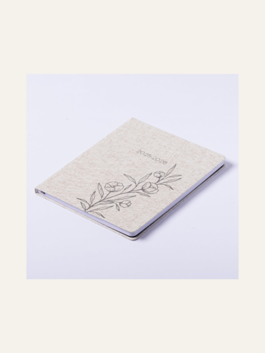 picture of a linen colored daily planner closed with sketch of flowers and 2025-2026 on it