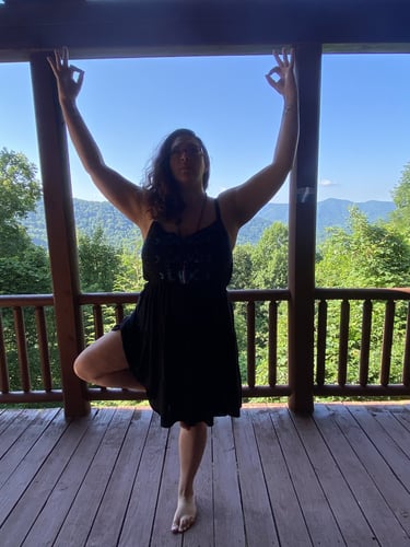 Rachel on balcony doing yoga with mountain range and tall trees and background