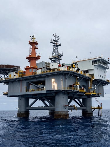 Low-angle heroic view of a completed offshore production platform in the Gulf of Mexico, high-contrast coastal sun reflecting off heavy steel structures.
