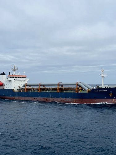 Wide-angle cinematic shot of a massive industrial pipe-laying vessel operating at sea under cool, overcast North Sea daylight, deep ocean blues, realistic maritime engineering.