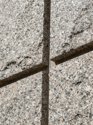 Low-angle close-up of interlocking granite stone joints, showing perfect alignment and geometric precision under bright sunlight