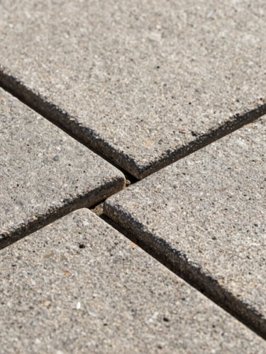 Close-up macro photo of interlocking natural stone paving joints, showing millimeter-precise alignment, clean geometric lines, harsh midday sun casting sharp shadows, highlighting texture and durability