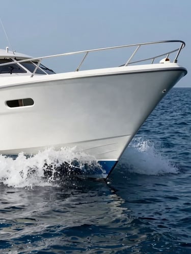 Low-angle dynamic water-level shot of a clean modern dayboat hull cutting through glassy deep blue Adriatic water, leaving a sharp white wake, crisp Mediterranean daylight.