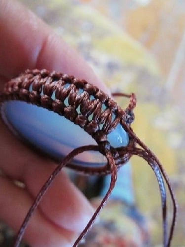 Un colgante de joyería personalizado está hecho a mano con un nudo de macramé marrón