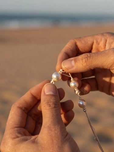 Hands of an artisan carefully weaving intricate micromacramé threads around a raw Sea of Cortez pearl, warm golden hour sunlight, soft desert shadows, macro focus on textures.