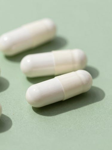 Macro photograph of clean white supplement capsules on a minimalist sage green surface, sharp clinical daylight, 35mm