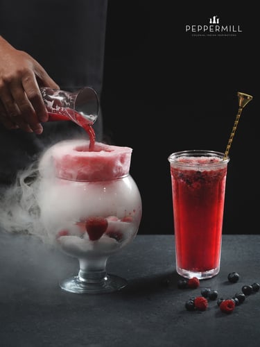 a person pouring a drink into a glass of ice cream