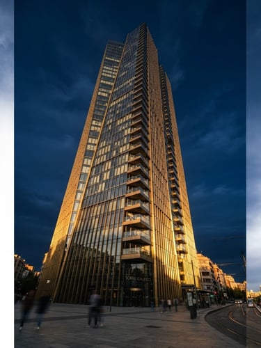 Low-angle architectural photography of a modern luxury high-rise building in Madrid, sharp golden-hour light reflecting off glass and brass, deep navy sky, editorial 35mm.