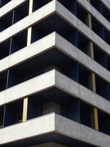 Wide architectural angle of a modern concrete and steel building facade, clean geometric lines, bright daylight, sharp contrast, deep navy shadows.