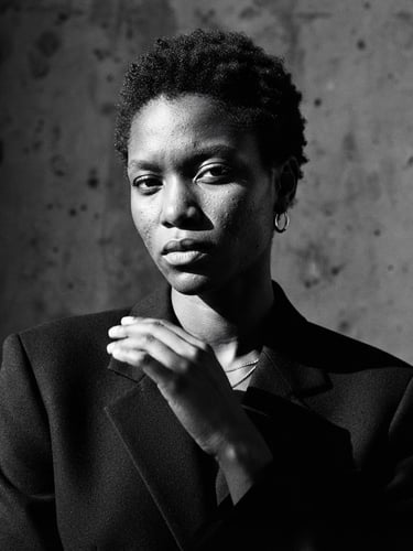 High-contrast editorial black and white portrait of a model with sharp direct sunlight and dramatic shadows, minimalist background, medium format film
