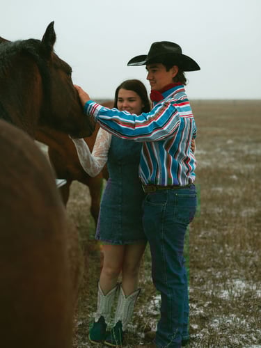 a man and woman standing in a field with horses