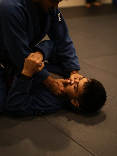 A martial arts instructor demonstrating a precise BJJ grip on a clean mat, close-up, dramatic low-key side lighting, deep charcoal and warm amber tones, 35mm lens, hands wrapped.
