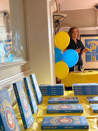 photo of a book launch with books on a table and balloons