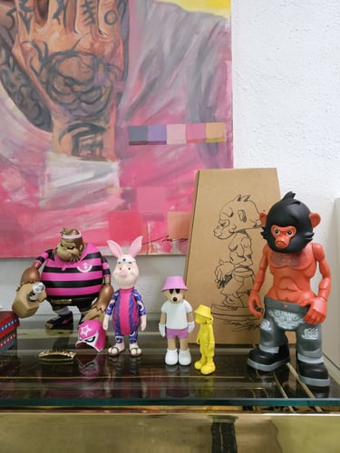 Collection of designer vinyl toy figures and urban art toys displayed on a glass shelf.