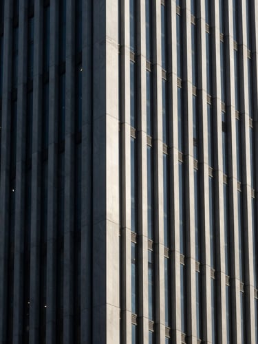 High-contrast architectural detail of modern Istanbul business district skyscraper facade, sharp natural side-lighting, deep obsidian shadows, clean vertical lines, minimal composition