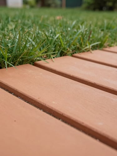 Low-angle shot of terracotta clay rubber tiles meeting lush green garden grass under soft overcast daylight, showing natural texture details and precise joint lines.