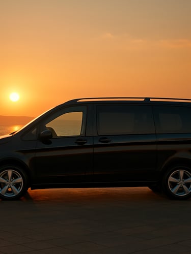 Side profile of a gleaming black Mercedes-Benz Vito parked on the İzmir Kordon coast at sunset, sea reflecting golden light, elegant composition.