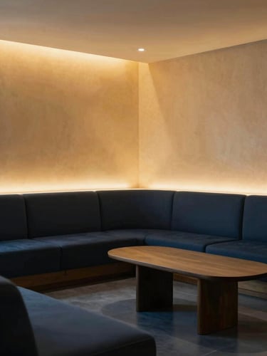 Wide architectural shot of the serene clinic lounge with soft side-lighting, deep navy and warm gold tones, elegant and calm.