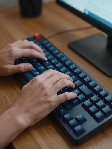Close-up of hands typing code on a mechanical keyboard, warm ambient light, soft blue screen glow reflecting on a wooden desk, 35mm.