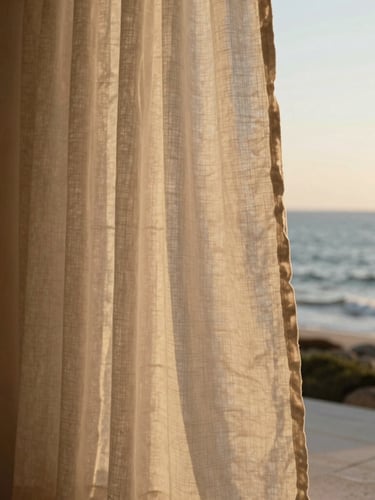 Soft-focus close-up of tactile linen curtains blowing in a gentle sea breeze, warm golden-hour light illuminating a minimalist stone interior.