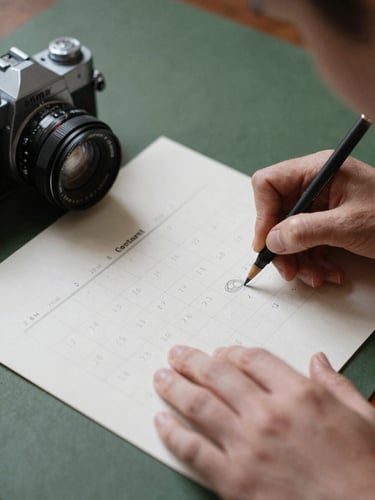 Intimate close-up of hands sketching a content calendar on parchment paper next to a vintage camera lens, soft Scandinavian natural light, 35mm