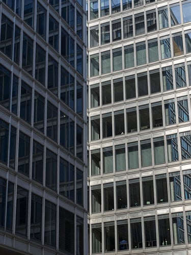 Cool corporate architecture, abstract geometric patterns of glass and steel, crisp daylight with subtle silver reflections, sharp focus, 35mm