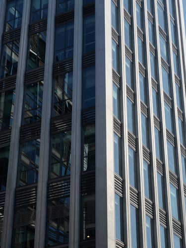 Cool corporate architecture with sharp glass and steel reflections, deep navy tones, crisp daylight, architectural angle, 35mm