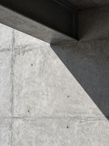 Close-up of a raw, perfectly poured concrete wall meeting a clean steel beam, sharp architectural lighting with deep shadows, precise textures.
