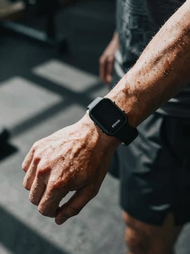 Dynamic close-up of a fitness creator's wrist with a technical wearable tracker, sweat drops, intense athletic training environment, dramatic shadows, 35mm.