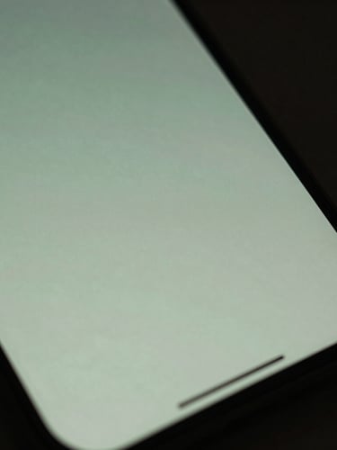 Macro close-up of a smartphone screen displaying a soft, glowing, minimalist interface with muted sage green tones, diffused dusk lighting