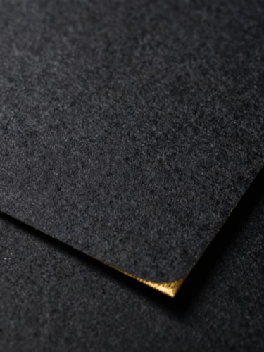 Macro texture of heavy dark cotton paper with a subtle gold-leaf edge, low-key dramatic lighting, extreme close-up, elegant and restrained.