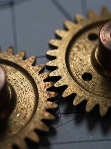 Macro detail of burnished brass mechanical gears, low-key chiaroscuro lighting with warm metallic reflections, technical blueprint lines faintly visible in the background, 35mm