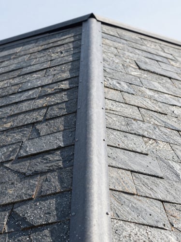 Crisp architectural close-up of metal flashing and clean shingle textures on a roof valley, bright natural daylight, showing high-contrast slate tones, 35mm lens.