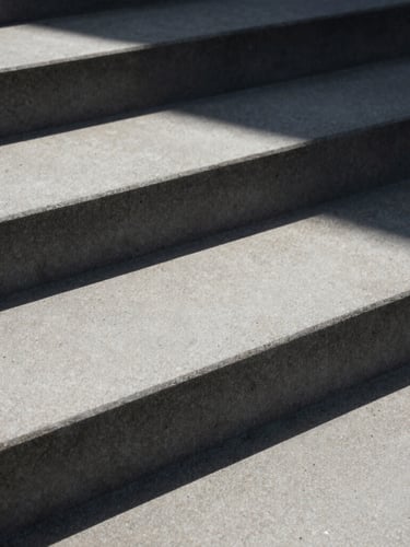 Macro close-up of sharp geometric concrete steps under harsh daylight, casting deep architectural shadows