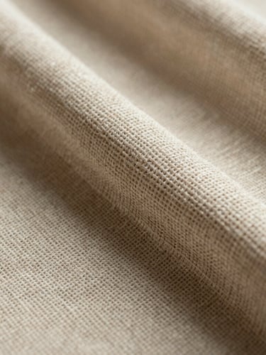 Macro texture shot of heavy-wear woven linen fabric, warm natural side-lighting highlighting the thick interlocking threads.