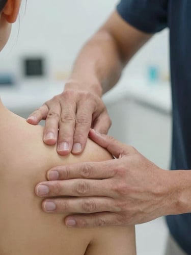 Close-up of an instructor guiding a student's hands during a manual shoulder mobilization technique on a patient in a bright, modern clinic.