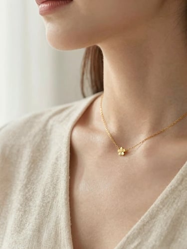 Close up of a woman's collarbone wearing a delicate gold necklace, soft morning light, cream linen background, shallow depth of field