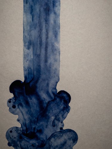 Macro architectural shot of deep indigo ink bleeding into heavy, warm stone-gray cotton paper, soft directional side-lighting casting subtle shadows, gallery exhibition feel.