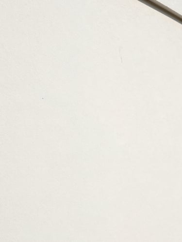 Gros plan architectural de l'angle d'un mur parfaitement lisse, peinture blanche mate uniforme, lumière rasante naturelle révélant l'absence totale de défaut