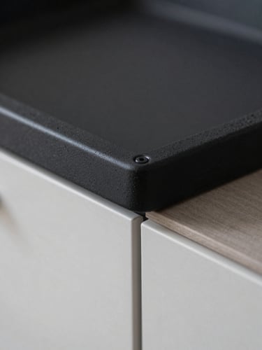 Détail macro d'une verrière d'atelier noire posée entre une cuisine et un salon, joints de silicone parfaits, raccord invisible avec le plâtre.