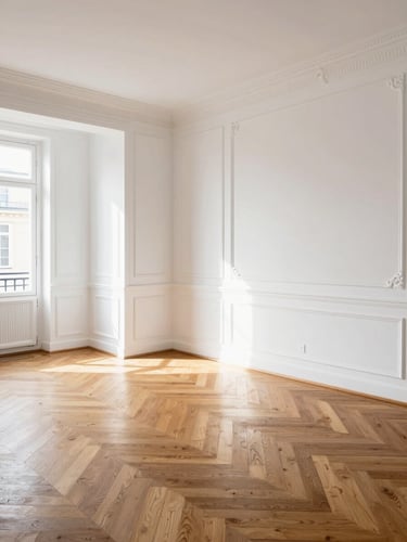 A brightly lit, renovated Parisian apartment living room with perfect white walls, restored oak herringbone parquet floor, and clean geometric lines, bathed in natural afternoon light.