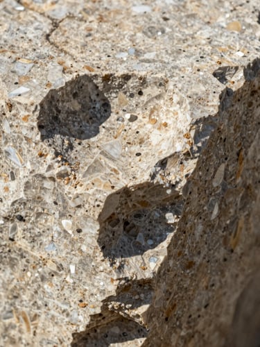 Macro texture detail of raw travertine stone under harsh direct sunlight, showing deep mineral crevices and sharp shadows