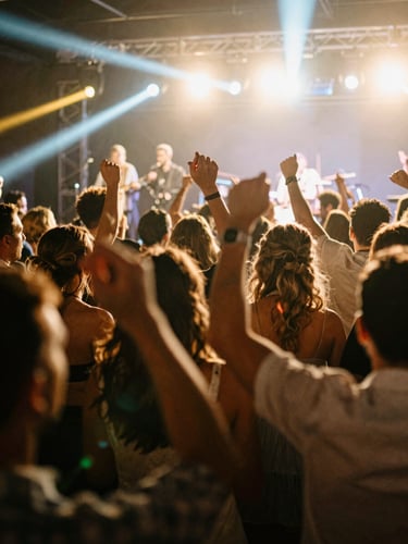 Dynamic low-angle shot of a wedding crowd dancing wildly under warm stage lights, band members partially visible on stage in the background, high contrast, motion blur, gritty live concert photography, 35mm film.