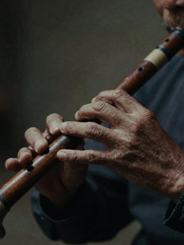 Extreme close-up of weathered hands playing a traditional wooden flute, low-key dramatic lighting, moody shadows, 35mm film grain