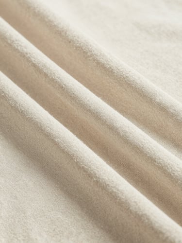 Close-up of soft beige linen fabric draped elegantly, showing fine weave texture, bright natural lighting