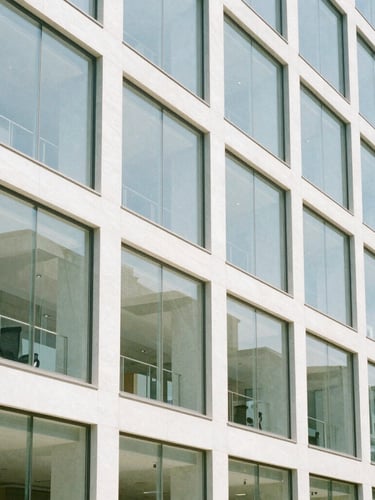 Bright daylight architectural shot of a modern clean glass office facade with sharp shadow lines, 35mm photography