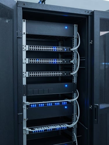 Immaculate server rack cabling in a cool-toned server room, clean organization, low-key blue indicator lights, sharp 35mm industrial photography