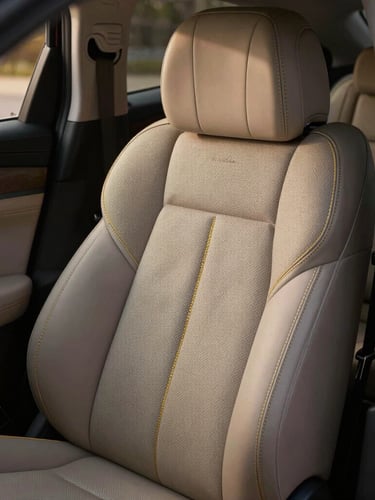 Close-up of Jaecoo J8 premium leather cabin seat with intricate golden stitching, soft ambient LED lighting casting a warm glow, luxury executive atmosphere