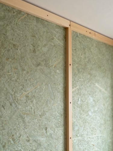 Medium close-up of a neatly finished internal wall showing wood fibre insulation boards, soft diffused side light, clean architectural detail
